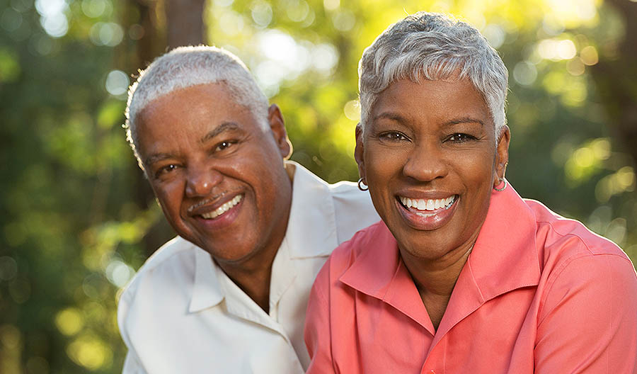 Smiling couple after their dental restoration procedures here in Long Beach.